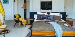 Μοντέρνα κρεβατοκάμαρα με πολυθρόνα δίπλα και λευκή ντουλάπα 