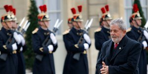 Ο Λουίς Ινάσιο Λούλα ντα Σίλβα με παλτό περπατά μπροστά από φρουρά
