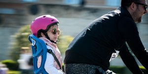 Μικρό κορίτσι με κράνος σε ειδικό κάθισμα σε ποδήλατο