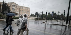 Πεζοί με ομπρέλες και αδιάβροχα