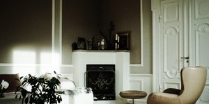 Σαλόνι διαμερίσματος με λευκή πόρτα, μπεζ πολυθρόνα, γλάστρα, τζάκι 