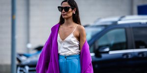 γυναίκα με ζακέτα και γυαλιά περπατά στο δρόμο