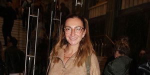 Η Ρούλα Ρέβη με τζιν και μπεζ παντελόνι, φοράει γυαλιά μυωπίας