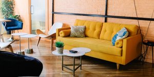 Σαλόνι διαμερίσματος στη Νέα Υόρκη με κίτρινο καναπέ, μπλε πολυθρίνα, λευκά τραπεζάκια