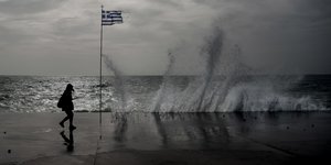 Ατομο περνάει δίπλα από ελληνική σημαία και κύμα