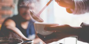 Γυναίκα βάζει σούπα σε ένα λευκό μπολ και αχνίζει