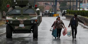 Ζευγάρι μεταφέρει σακούλες δίπλα από όχημα του στρατού στη Βολιβία