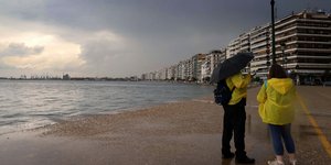 Ανθρωποι με κίτρινα αδιάβροχα και ομπρέλα στη παραλία της Θεσσαλονίκης