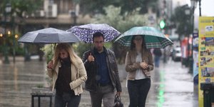 Κόσμος περπατάει με ομπρέλες
