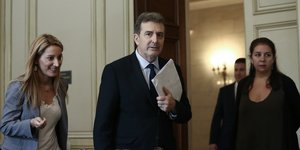 Ο Μιχάλης Χρυσοχοϊδης κρατάει χαρτιά σε αίθουσα