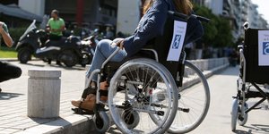 Γυναίκα σε αναπηρικό καροτσάκι ανεβαίνει σε πεζοδρόμιο