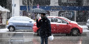 Ανδρας περπατάει με ομπρέλα στο χιόνι