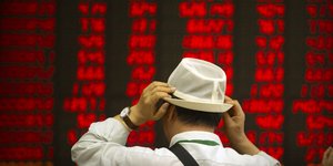 Άνδρας μπροστά σε κατακόκκινο από την πτώση πίνακα μετοχών του χρηματιστηρίου