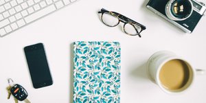 Καφές, γυαλιά, φωτογραφική μηχανή, κλειδιά και τετράδιο πάνω σε λευκό τραπέζι 