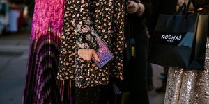 Γυναίκα φοράει φλοράλ πανωφόρι και κρατάει clutch