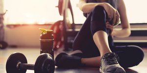 Γυναίκα κάθεται στο πάτωμα μετά από γυμναστική