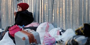 Γυναίκα κάθετε δίπλα σε βαλίτσες και σακούλες
