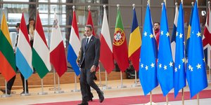 O Κυριάκος Μητσοτάκης περπατάει σε διάδρομο με σημαίες