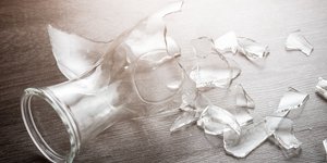 Σπασμένο ποτήρι σε ξύλινο πάτωμα