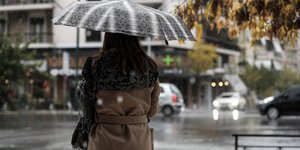 Γυναίκα στέκεται με ομπρέλα στη βροχή