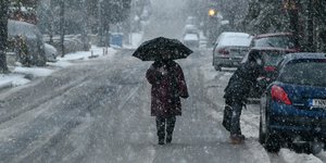 Γυναίκα περπατά με ομπρέλα στο χιόνι