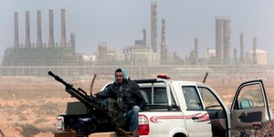Μαχητής κατά της κυβέρνησης αλ Σάρατζ με φόντο το διυλιστήριο του Ρας Λανούφ στην ανατολική Λιβύη