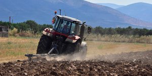 Αγρότης με τρακτέρ σε χωράφι