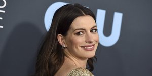 Η Αν Χάθαγουεϊ με χρυσό φόρεμα χαμογελά