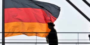 Ανθρωποι περνούν μπροστά από τη σημαία της Γερμανίας