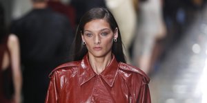 γυναίκα με κόκκινο δερμάτινο παλτό περπατά στο σόου της Bottega Veneta