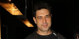 O Μπουράκ Χακί με μαύρη μπλούζα και χακί πουκάμισο κρατάει ένα μπουκάλι νερό