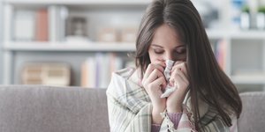 Γυναίκα άρρωστη στον καναπέ με χαρτομάντιλο