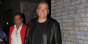 Ο Γιώργος Λιάγκας χαμογελαστός με δερμάτινο τζάκετ