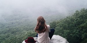 Γυναίκα κάθεται πλάτη και φορά καρό πουκάμισο με θέα δάσος