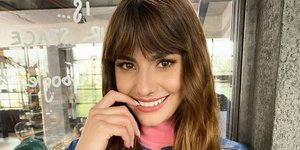 H Hλιάνα Παπαγεωργίου με τζιν φόρεμα και ροζ τοπ χαμογελά στον φακό 