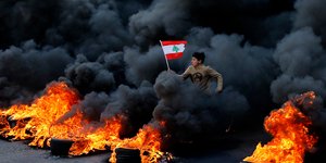 Νεαρός τρέχει μέσα από καπνούς και φωτιά στον Λίβανο