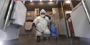 Άνδρας με στολή και μάσκα σε κτίριο της Κίνας, μετά την εξάπλωση του κοροναϊού