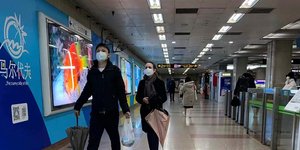 Κινέζοι με μάσκες περπατούν σε σταθμό