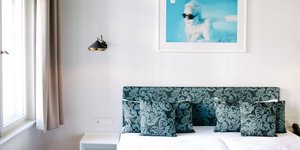 Κρεβατοκάμαρα διαμερίσματος με κρεβάτι, φωτιστικό, πίνακα, κομοδίνο