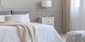 Κρεβάτι με λευκό πάπλωμα και λευκό κομοδίνο