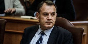 Ο Νίκος Παναγιωτόπουλος, καθιστός, με γαλάζιο πουκάμισο