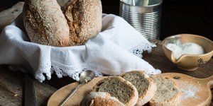 Ψωμιά μέσα σε καλάθι και φέτες ψωμιού σε ξύλο κοπής