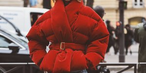 γυναίκα με κόκκινο puffer τζάκετ και τζιν στην εβδομάδα μόδας