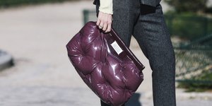 γυναίκα με καπιτονέ τσάντα και παντελόνι στέκεται στο δρόμο