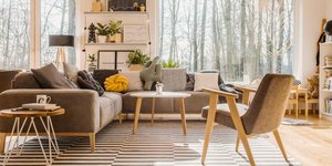 Γκρι καναπές σε σαλόνι και ριγέ χαλί στο κέντρο 