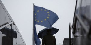 Άνδρας με ομπρέλα έξω από τα κτίρια της ΕΕ στις Βρυξέλλες