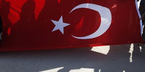 Σκιές διαδηλωτών που κρατούν τη σημαία της Τουρκίας
