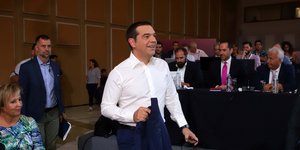 O Αλέξης Τσίπρας μπαίνει σε αίθουσα κρατώντας το σακάκι στο χέρι