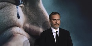 Ο Joaquin Phoenix μπροστά από αφίσα του Joker