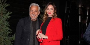 Ο Χάρης Χριστόπουλος χαμογελάει και η Ανίτα Μπραντ φοράει κόκκινο κοστούμι